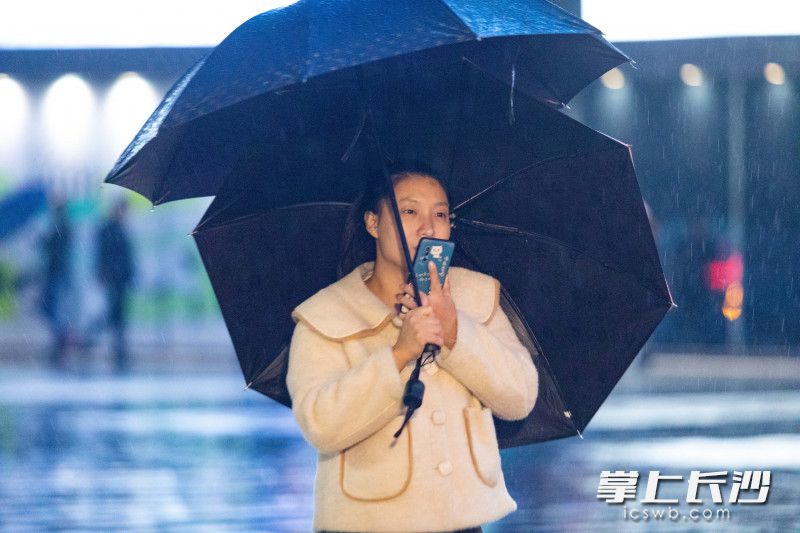 一位女子撑起了两把雨伞，一把遮风，一把避雨。