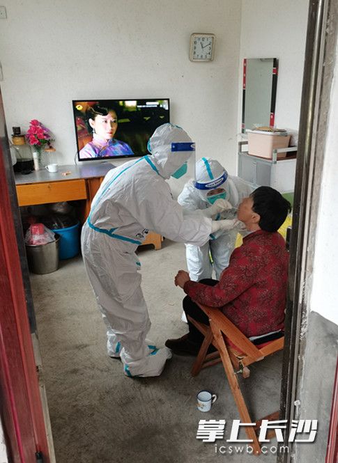 防疫医疗队员走村入户，给行动不便的老人开展核酸采样。