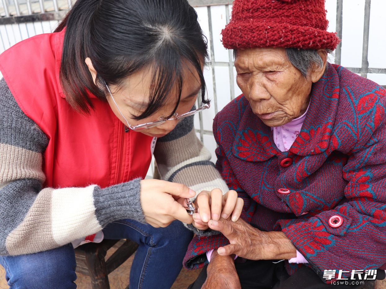大成桥镇巾帼志愿服务队上门看望高龄老人，并细心地为老人修剪指甲。