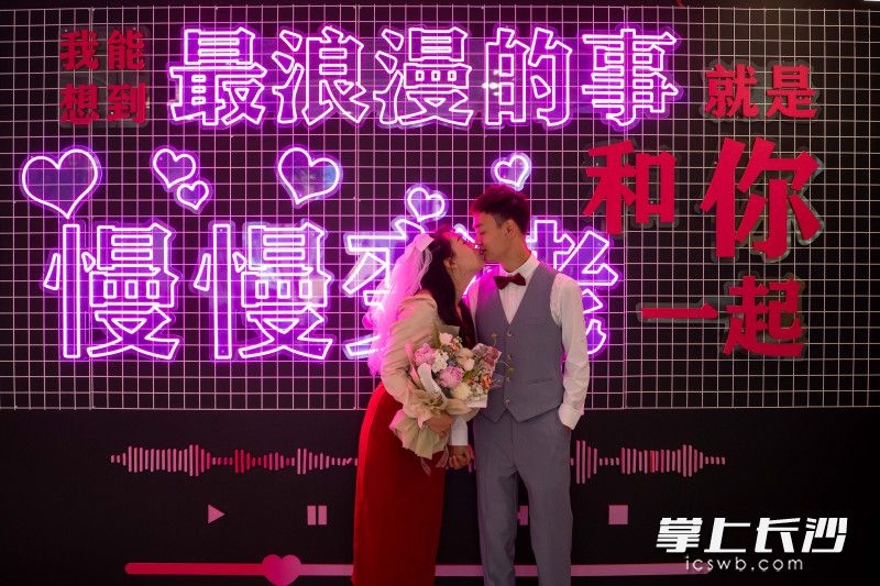 一对新人在芙蓉区民政局婚姻登记处“中国黄金街”登记点的表白墙前亲吻。