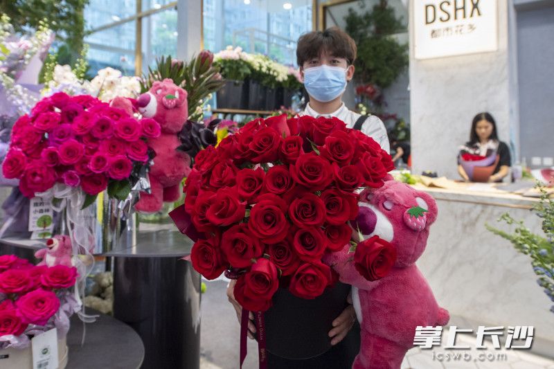 花店店员在向记者展示该店销售最火热的“抱抱熊”花束。