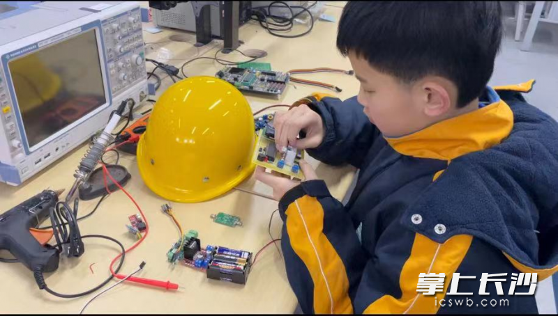 李逸凡正在制作组装“盲人智能安全行走帽”。学校供图