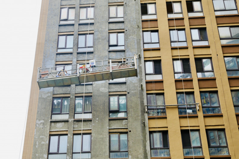 31层高楼大“换肤”，工人化身“蜘蛛人”高空作业精细施工。