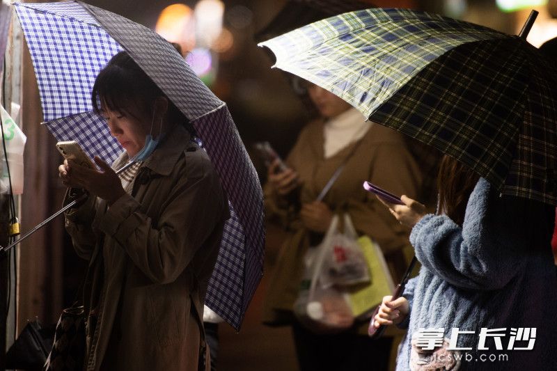 在东二环一家麻辣烫店前，市民撑着雨伞扫码点单。