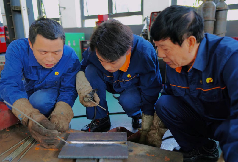艾爱国（右一）、欧勇（左一）示范焊条电弧焊的操作技巧。