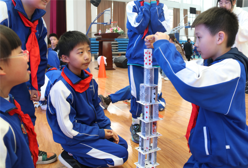 几名同学正在进行“纸牌搭高塔”。