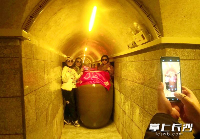游客在麻姑井糯米黄酒酿造文化园的地下酒窖里参观打卡。