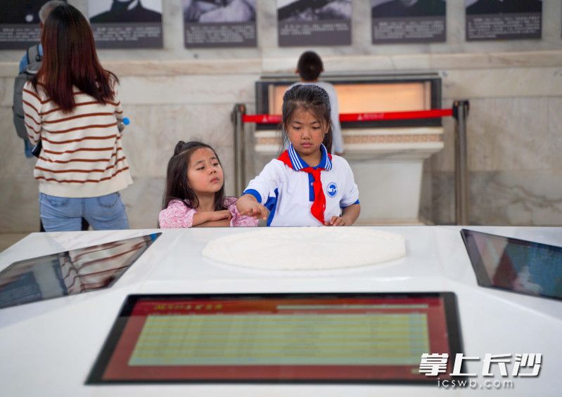 湖南烈士公园纪念塔内，2名小女孩正在通过智慧设备了解湖南革命烈士的英勇事迹。