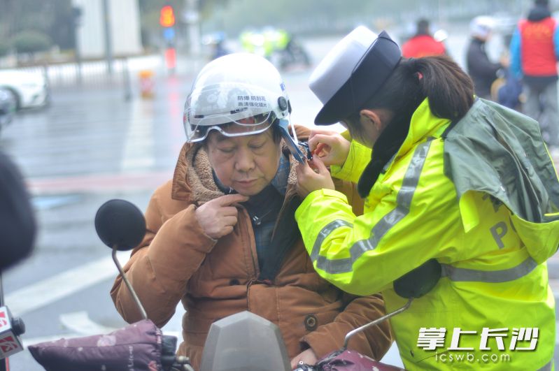 交警帮驾驶人戴上安全头盔。