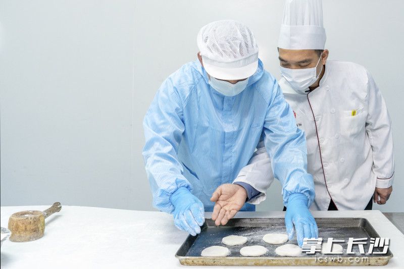 韦佳辰正提醒着员工法饼制作中装盘烘焙的注意事项。