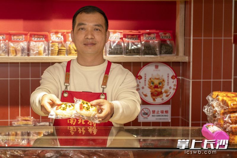 韦佳辰面带微笑，向顾客展示店内的特色产品“法饼”。