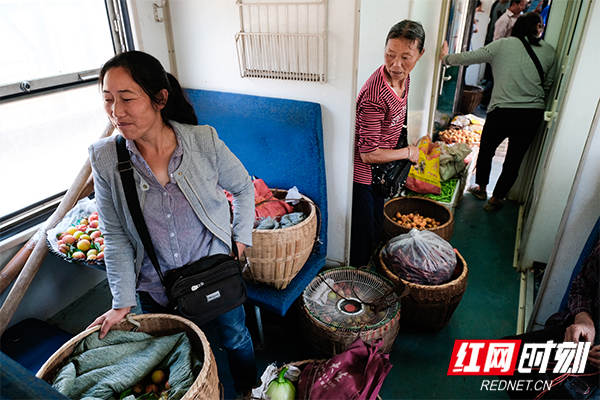 当列车抵达锦和站时，很多农民挑着满担的水果和蔬菜上车。
