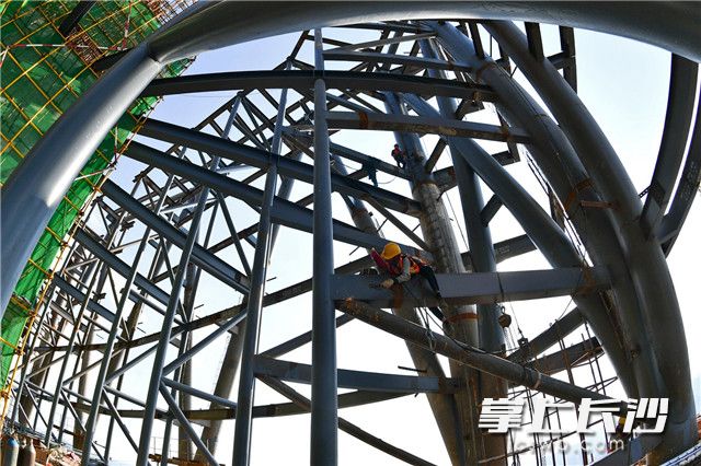 在328米高楼顶，李运富和工友们须爬上10多米的钢架，将钢结构天衣无缝地拼接在一起。