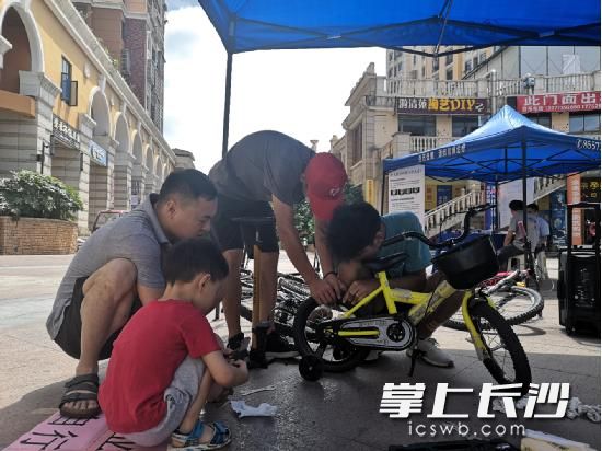 湖南工业职院自行车协会正在给居民提供自行车修理服务。