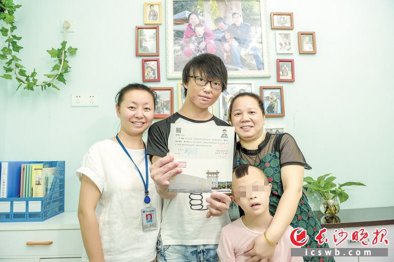 　　福利院的类家庭出了个大学生，范鸿宇（左二）和“妈妈”“弟弟”以及福利院工作人员合影。长沙晚报全媒体记者 陈飞 摄