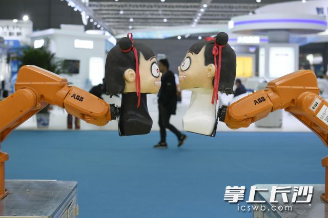 在一个机器人展台，两个娃娃造型的机器人在跳舞。