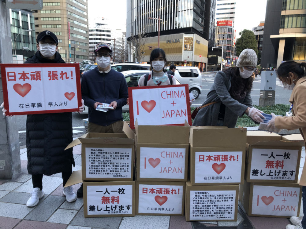 2月20日，在日本名古屋，在日华侨华人志愿者团体成员向当地民众发放口罩。新华社发（雪宏 摄）