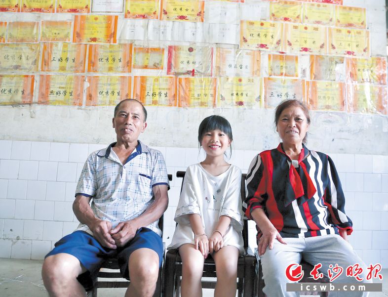 　▲采访当天，姐姐去浏阳城里了，妹妹李湘和爷爷奶奶在奖状墙前开心合影。长沙晚报全媒体记者 颜开云 摄