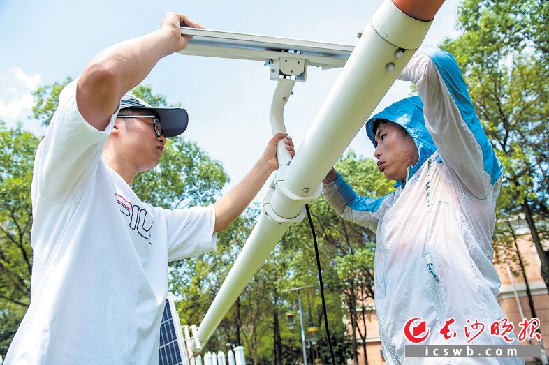 　　烈日下，工程师崔强和江任远正在给风杆安装太阳能面板。