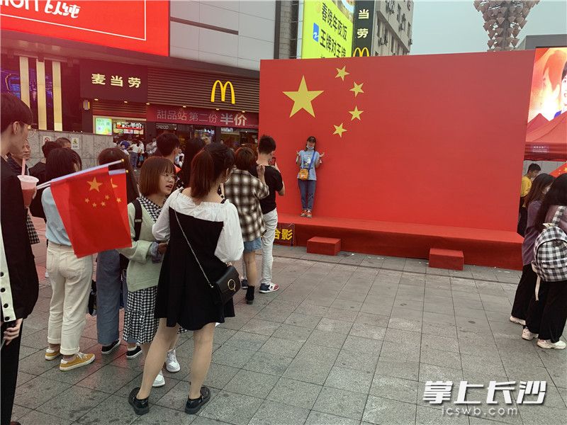10月1日，黄兴南路步行商业街巨型国旗前，排队拍照的游客众多。