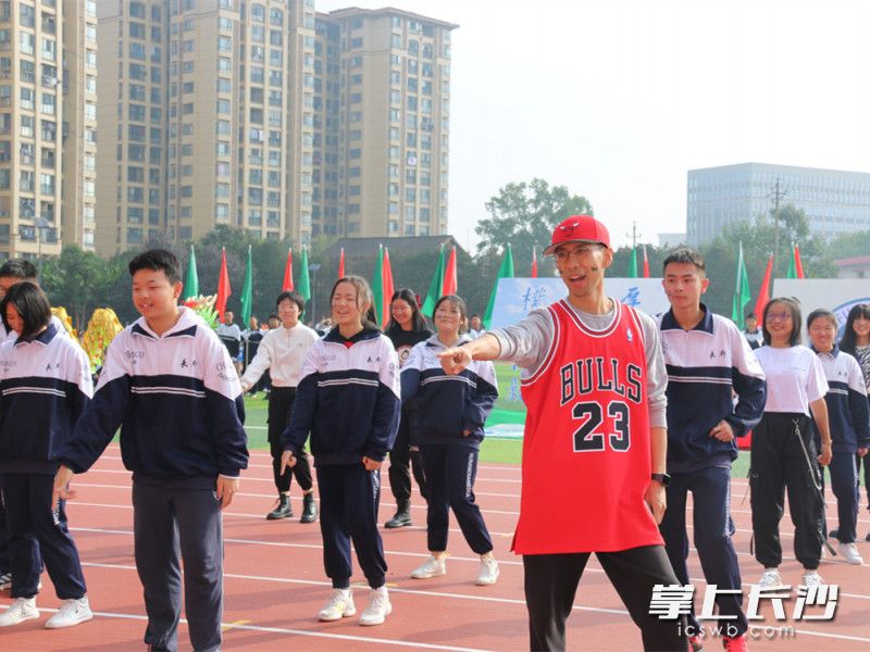 金亚骏（红衣）在校运会开幕式上和学生一起跳舞。 长沙晚报全媒体记者 刘俊 摄
