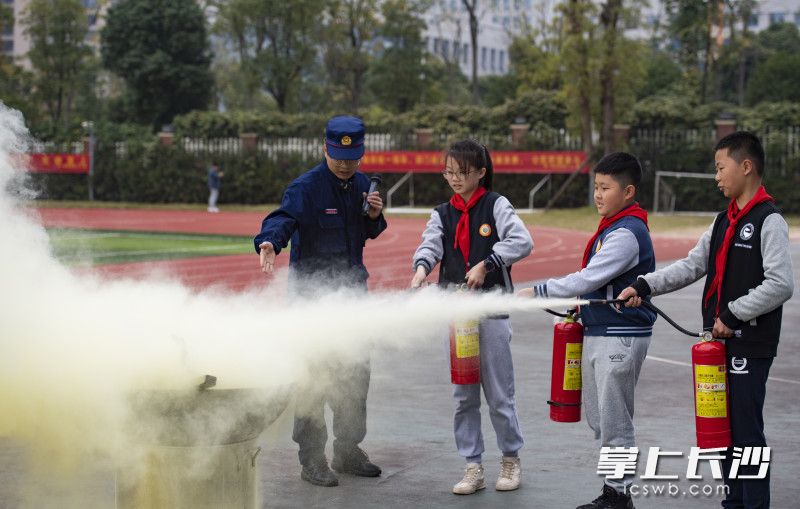 学生们在消防员的指导下，正确使用灭火器灭火。