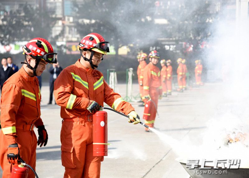 消防指战员使用灭火器扑灭油锅“火灾”。