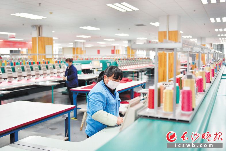 梦洁家纺生产车间内，戴着口罩的工人在有序生产。