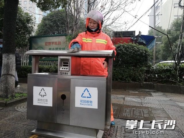 妻子刘先桃正在清洁街头垃圾桶。