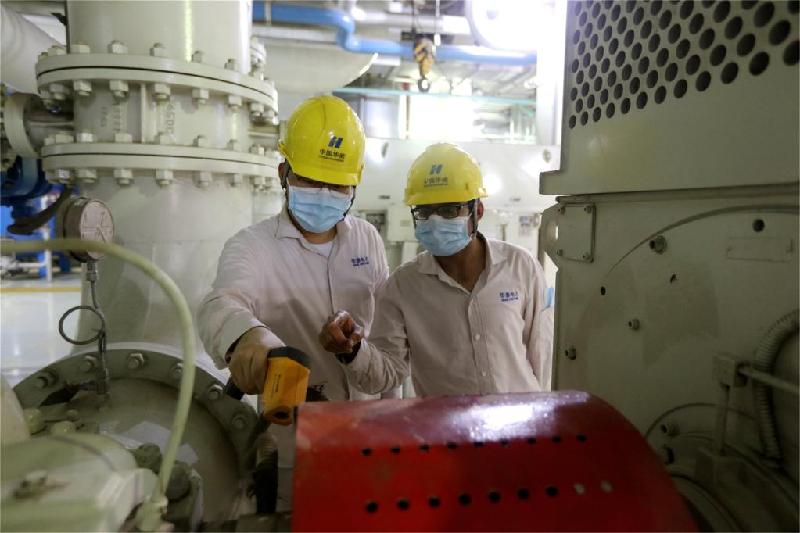 穆尼卜（右）与中国同事在检查设备运行情况。