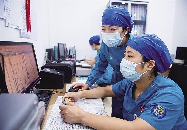 在湖南省人民医院ICU病房护士站，徐芙蓉（中）和同事查看病人住院记录（九月九日摄）