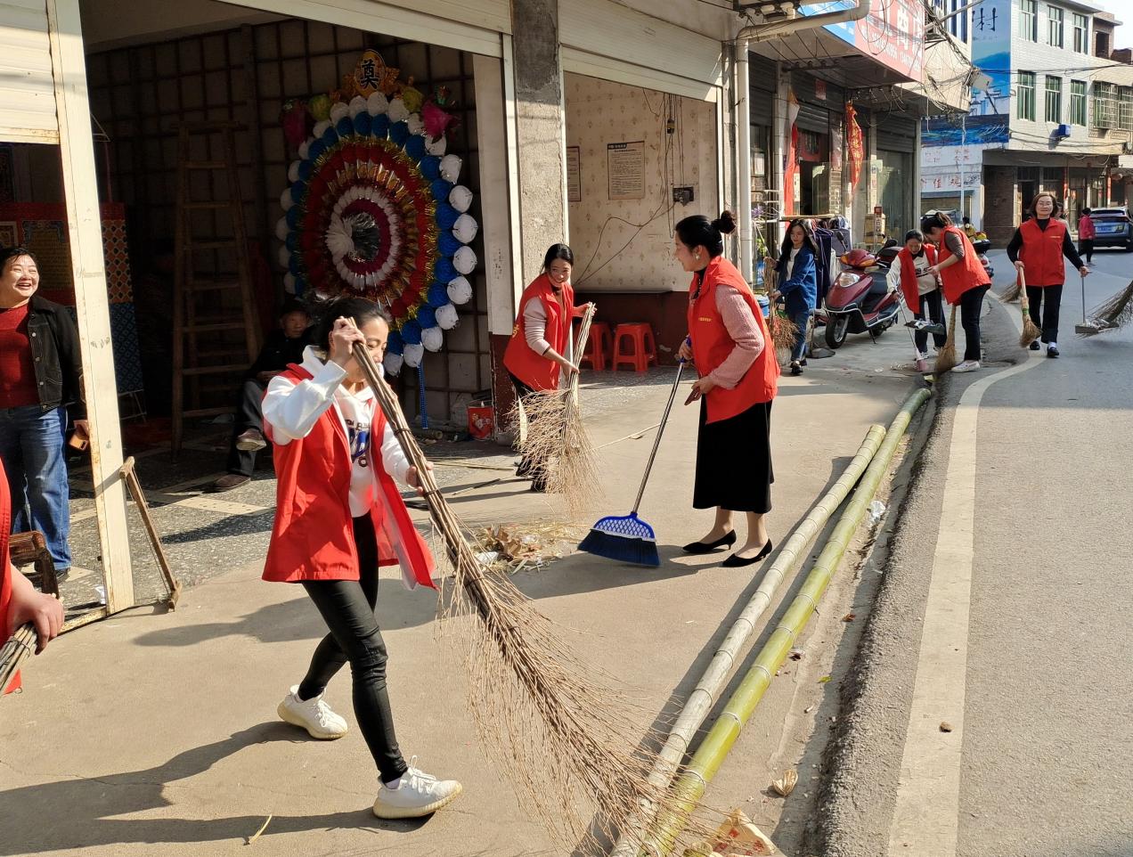 华园村巾帼志愿者义务清扫街道。