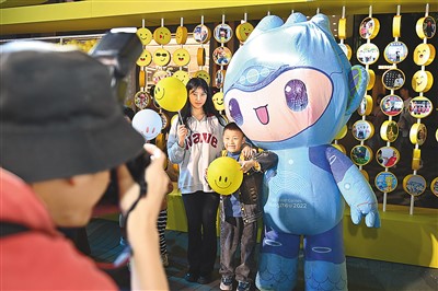 5月7日，在浙江省杭州市湖滨步行街“3D笑脸墙”前，摄影师为游客与杭州亚运会吉祥物之一“宸宸”拍摄合影。新华社记者 黄宗治 摄